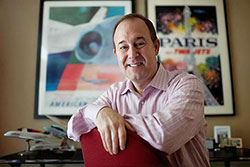 Portrait of Henry Harteveldt in his office with vintage travel posters behind him.