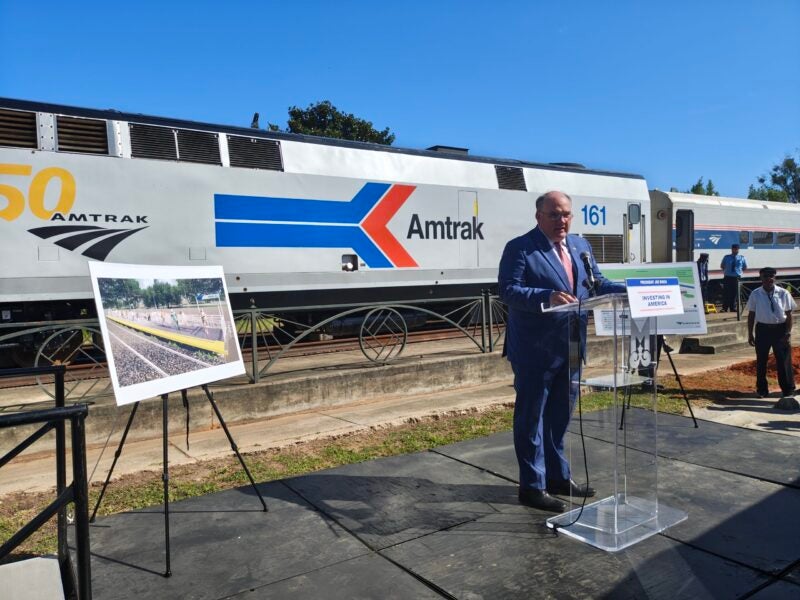 Provided image of Knox Ross speaking in front of Amtrak train in Mobile.
